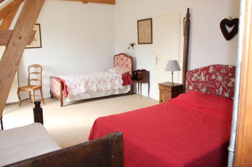 1 dormitorio con 2 camas y 1 silla en Le prieure, en Raslay