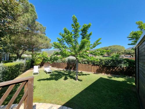 a yard with a fence and a tree and chairs at Camping Lacona Pineta in Capoliveri