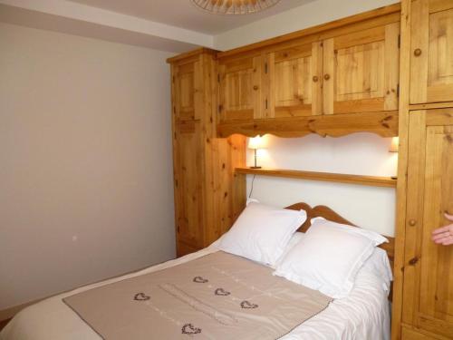 een slaapkamer met een bed met witte lakens en houten kasten bij Les noisettes in Lhommaizé