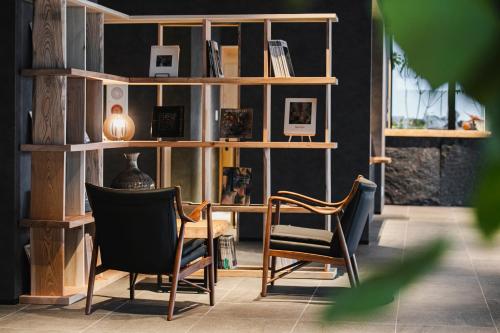 um quarto com duas cadeiras e uma estante de livros em MURE Beppu em Beppu