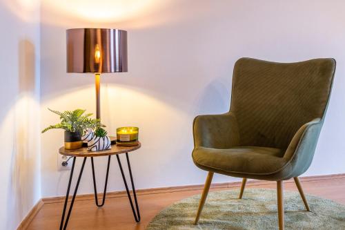 a green chair and a table with a lamp at Primavera - Castle view apartments in Prague