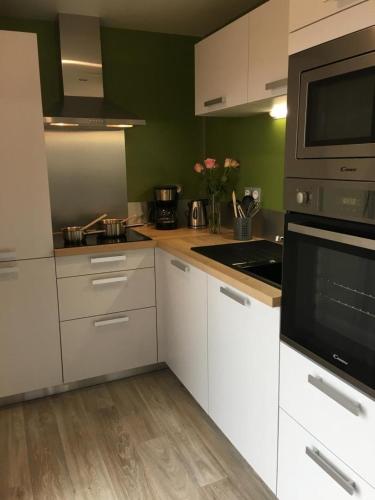La cuisine est équipée de placards blancs et d'un four micro-ondes noir. dans l'établissement Pistache la vallee des noyers, à Lhommaizé