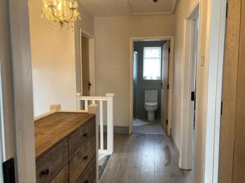 La salle de bains est pourvue d'une commode en bois et de toilettes. dans l'établissement Peaceful Home in Guildford Surrey UK -Free Parking, Garden, River & Waterfall, à Bramley