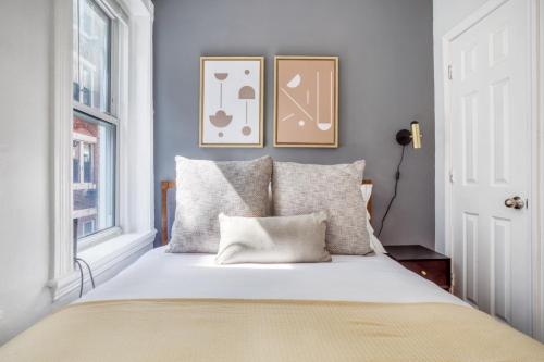 1 dormitorio con 1 cama con 2 cuadros en la pared en Cozy N End 2BR steps from Harborwalk BOS-445, en Boston