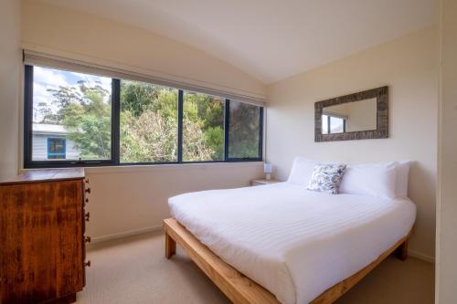 Un dormitorio con una cama grande y una ventana. en Haven on Bradley, en Coles Bay