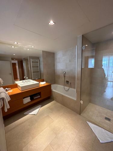 a bathroom with a tub and a sink and a shower at Golf & Relax Apartment mit 4*S-Anbindung in Bad Waltersdorf