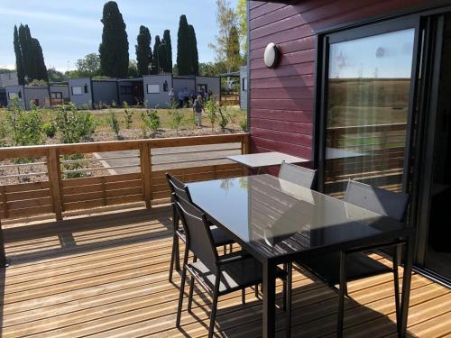 d'une terrasse avec une table en verre et des chaises. dans l'établissement Hibiscus la vallee des noyers, à Lhommaizé