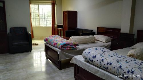 una habitación con 3 camas y una silla. en HOTEL MOHSIN PLAZA, en Sreemangal