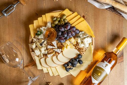 a table topped with cheese and fruit and a bottle of wine at Hotel Salvador in Batumi