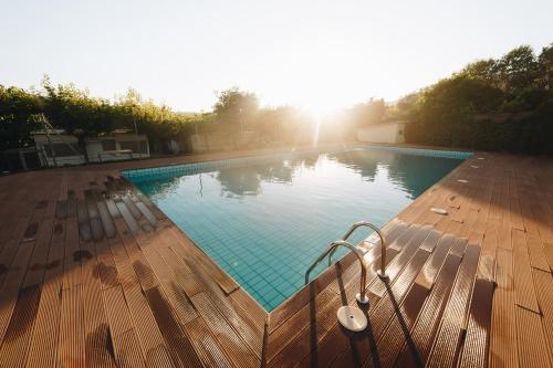 a swimming pool on a wooden deck with the sun setting at Vall d'Àger Resort & Camping in Ager