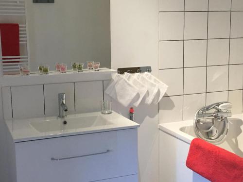 Baño blanco con lavabo y toalla roja en Le gite de scevolles, en Verrue