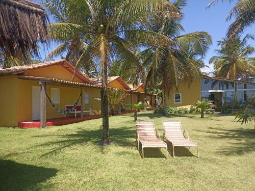 tres sillas sentadas en un patio junto a una casa en Pousada Flor de Elisa frente a praia, en Caraíva