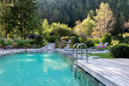una gran piscina con una terraza de madera y un bosque en Hotel Burgfrieden en Gais