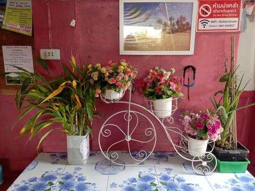 a flower stand with three potted plants on a wall at Sabaydee House at Pai in Pai