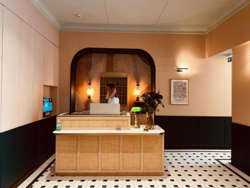 a lobby with a reception desk and a woman in the mirror at Hôtel De Londres in Menton