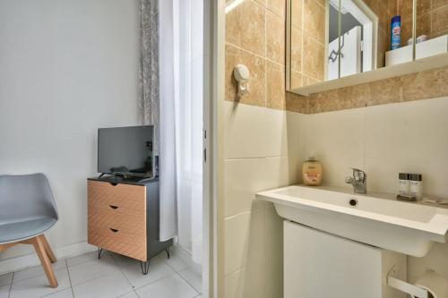 uma casa de banho com um lavatório e uma televisão num armário em Magnificent studio near Paris em Clichy