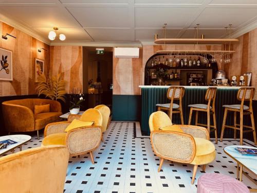 a restaurant with yellow chairs and a bar at Hôtel De Londres in Menton