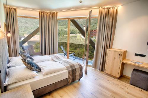 a bedroom with a bed and a large window at Genusshotel Diamant in Naturno
