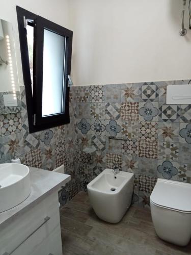 a bathroom with a sink and a toilet and a mirror at La dimora del cavatore in Favignana