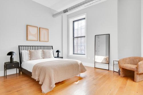 ein weißes Schlafzimmer mit einem Bett und einem Stuhl in der Unterkunft Jersey City 2BR w WD DM free shuttle to PATH NYC-761 in Hoboken