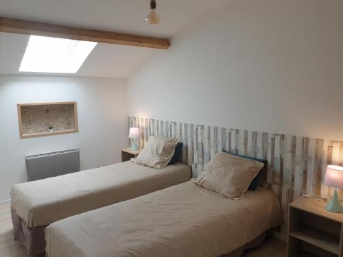 two beds in a small room with two lamps at La maison poitevine in Chauvigny