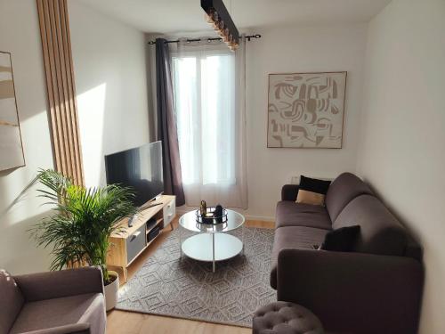 een woonkamer met een bank en een tv bij Superbe appartement proche la défense et Paris in Bezons