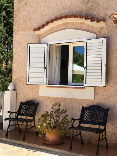dos bancos sentados frente a una ventana con persianas en Villa Casa Diego Ibiza, en Santa Eulària des Riu