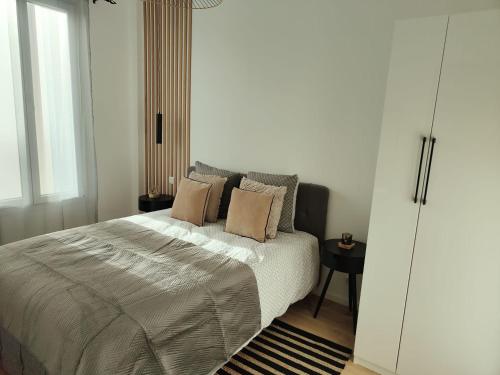 een slaapkamer met een bed met kussens erop bij Superbe appartement proche la défense et Paris in Bezons