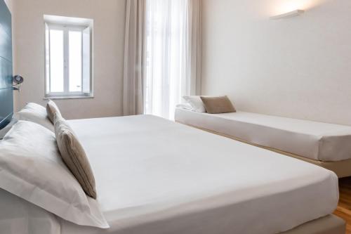 two white beds in a room with a window at Hotel Piazza Bellini & Apartments in Naples