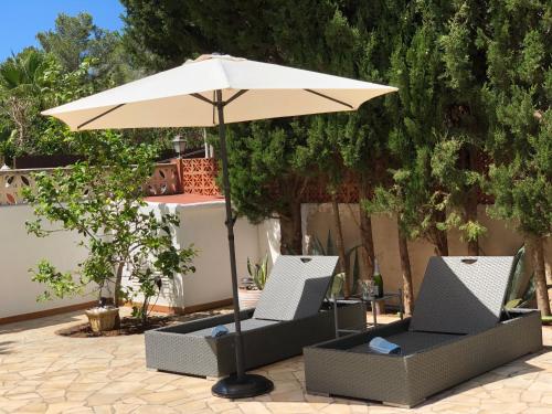 an umbrella and two chairs under a table at Villa Casa Diego Ibiza in Santa Eularia des Riu