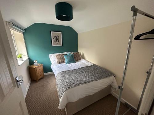 1 dormitorio con 1 cama con pared verde en Number 3 Seafield - sleeps 4 - Grantham town, en Lincolnshire
