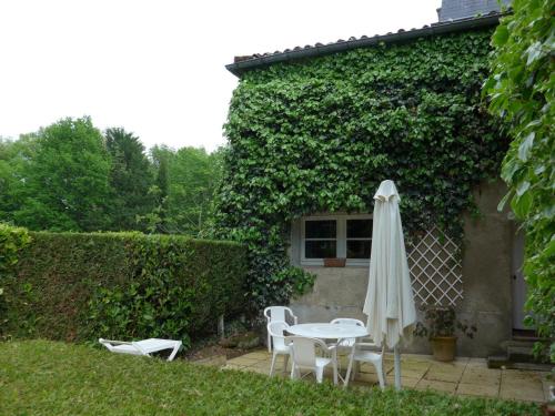 een patio met een tafel en stoelen en een parasol bij La rouartiniere in Mignaloux-Beauvoir