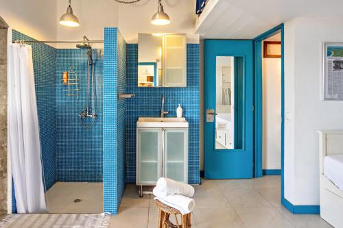 a bathroom with a sink and a shower with blue tiles at Casa da Praia in Vila Baleira
