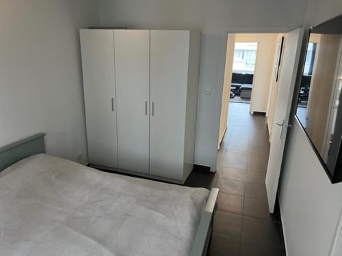 una camera con letto, armadi bianchi e corridoio di Appartement Wim a Blankenberge