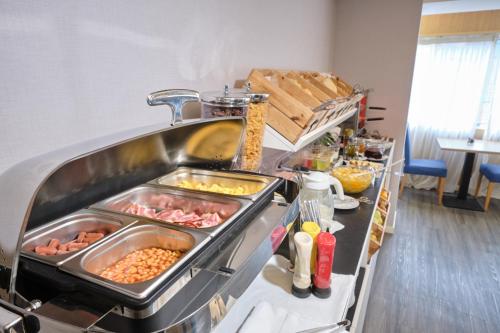 a kitchen with many trays of food on a counter at Patria Hotel in Lisbon
