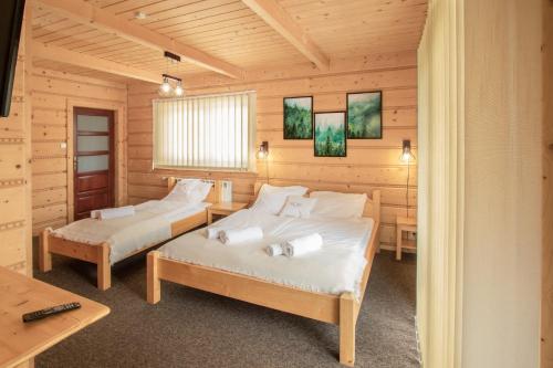 2 łóżka w pokoju z drewnianymi ścianami w obiekcie Chochołowskie Zacisze przy Termach - Apartamenty i Pokoje w Chochołowie