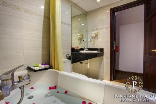 y baño con bañera blanca y lavamanos. en Parklane Central Hanoi Hotel, en Hanói