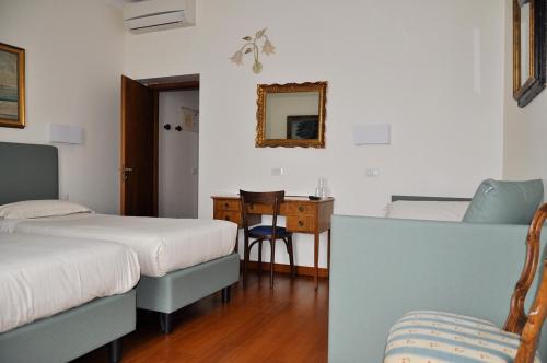 a room with two beds and a table and a mirror at Hotel San Guido in Milan