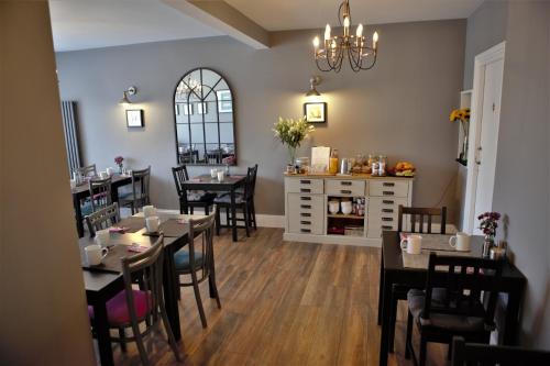una sala da pranzo con tavoli, sedie e lampadario a braccio di Skyline Guesthouse a Newquay