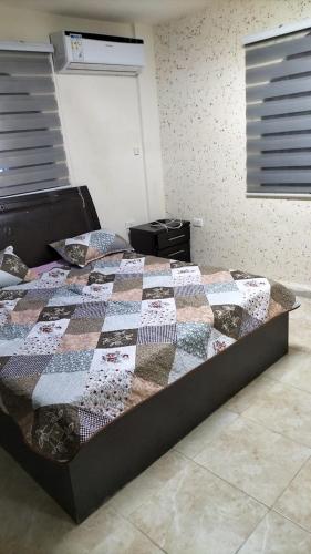 a bed with a quilt on it in a room at SARA HOME 2 in Al Kafrayn