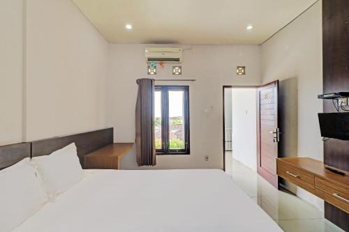 a bedroom with a large white bed and a window at OYO 92315 Prostay Bali in Denpasar