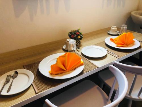 una mesa con platos blancos y servilletas naranjas. en Cannel view apartment Negombo en Negombo