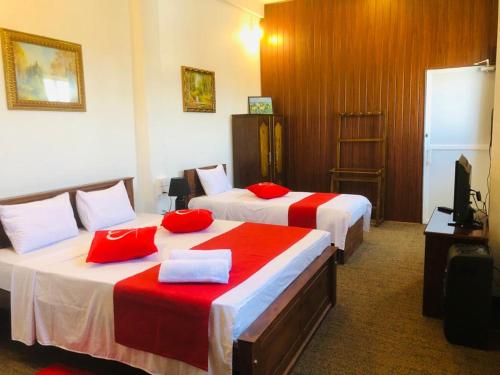 Cannel view apartment Negombo في نيجومبو: سريرين في غرفة الفندق مع وسائد حمراء