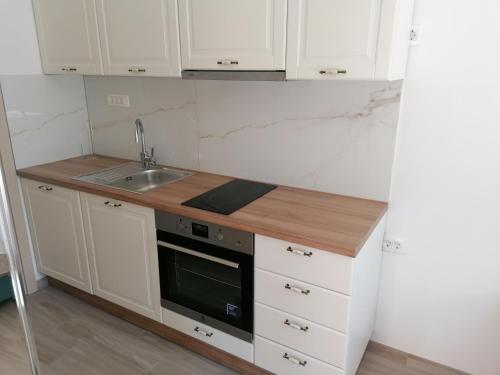 una cocina con armarios blancos y fregadero en Apartments and Rooms Tomas, en Podstrana