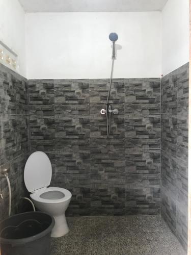 uma casa de banho com um WC e uma parede de tijolos em Makini Guest House em Lambangkuning
