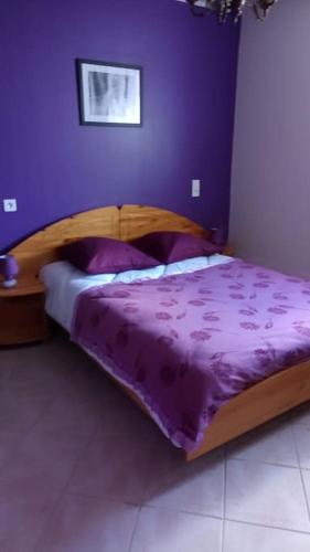 - un lit avec une couette violette dans une chambre dans l'établissement Gîtes les Floralies Le Magnolia, à Neuve-Église