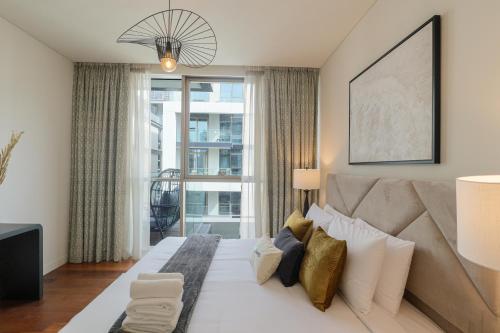 - une chambre avec un grand lit et une grande fenêtre dans l'établissement HiGuests - Charming Retreat in CityWalk With Balcony and Pool, à Dubaï