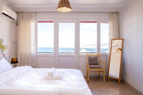 a bedroom with a bed and a chair and windows at Lovely House with Sea View and Backyard in İzmir