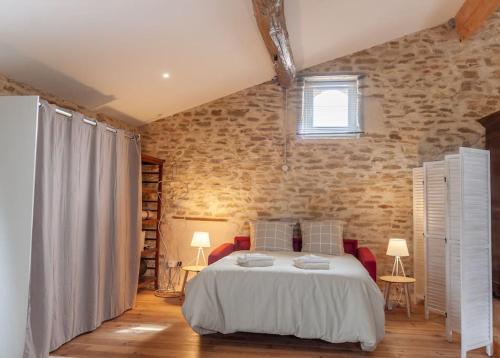 a bedroom with a bed and a brick wall at La Grange de Johanni in Davayé