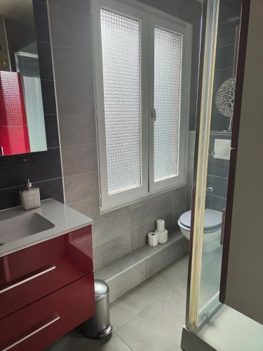 La salle de bains est pourvue de toilettes, d'un lavabo et de 2 fenêtres. dans l'établissement L appart de la place Ste Catherine, à Honfleur